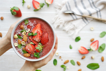 Female hands hold a bowl of strawberry smoothie. Healthy lifestyle, healthy eating, dieting concept 