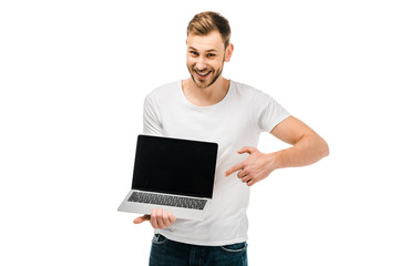 happy young man pointing with finger at laptop with blank screen isolated on white