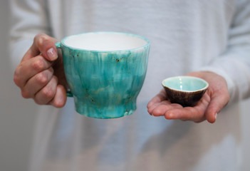 Ceramic mugs on the background of pastel colors in the hands of a woman