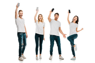 Obraz premium full length view of happy young men and women holding smartphones and smiling at camera isolated on white