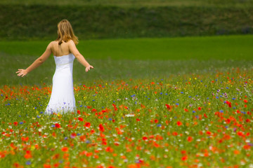 blonde girl dressed in white in a field of flowers