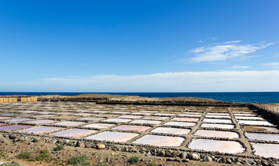 Pozo Izquierdo salt mines at Tenefe cultural park with calm sea on background on sunny day in Gran Canaria, Spain. Saltpans production factory in Canary Islands