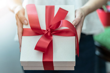 Give gift. Close up on woman hands holding a white gift box with red ribbon presents Symbol of love,Share, valentine day, birthday, mother's day,celebrate, Happy new year. Giving, receiving surprise