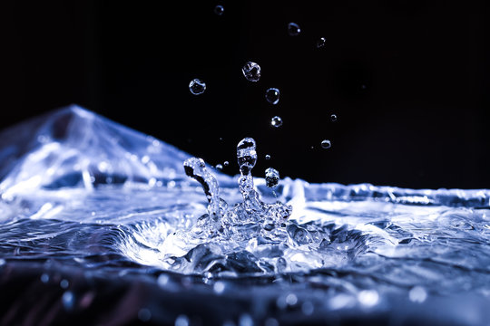 Water drops splashing on acoustic membrane. A lot of drops in air. High frequency of sound waves. Water cloud small drops. Frozen time shot.