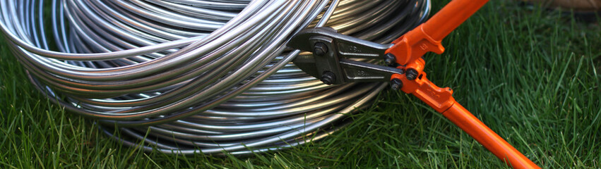 Aluminum wire in the bay on the background of grass, trimmed with a bolt cutter