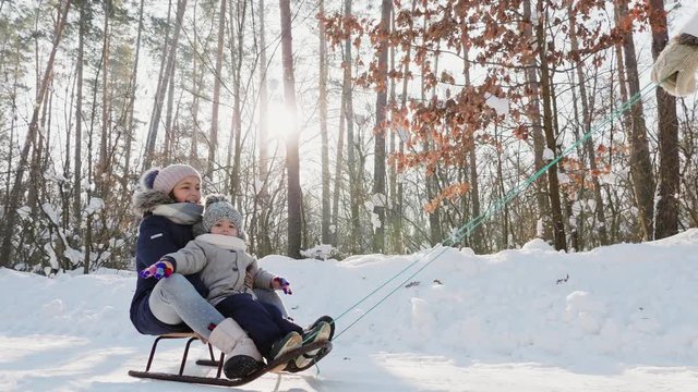 Unrecognizable mother pulling sled with kids