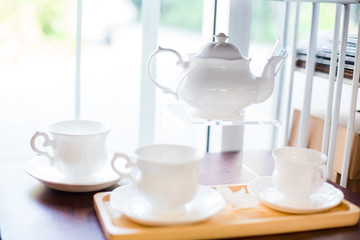 cup and kettle white ceramic on shelves