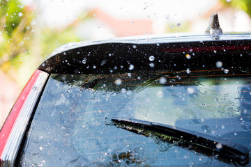 The wiper on rear window of a car with drop rain - obrazy, fototapety, plakaty