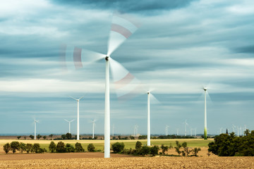 Windräder drehen sich, bewölkter stürmischer Himmel, abgeerntete Felder