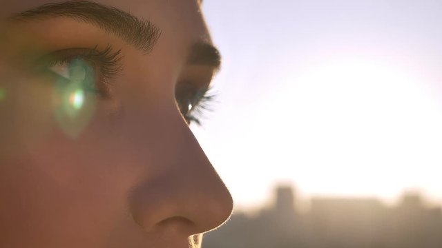 Closeup portrait of young beautiful female eyes looking forward. Woman in hijab with sun shining on the background