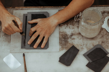 Close up of master making leather wallet with brush and glue. Handmade master at work in local workshop. Handmade concept. Top view