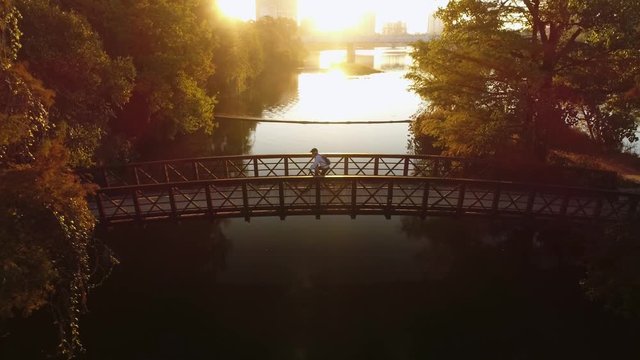 Cyclist and Four Women Cross a Bridge at Sunrise
