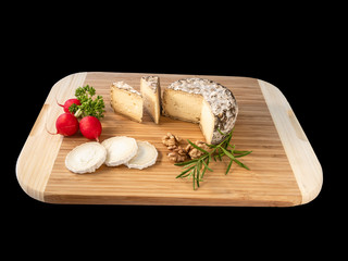 Cheese from France named Tommette des Alpes and white round goat cheese with nuts and parsley on the black background with shadow