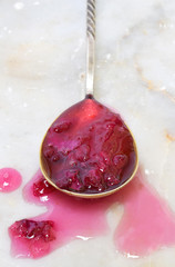 Jam of tea rose petal in spoon on light marble background. Flower confiture. Healthy food. Copy...
