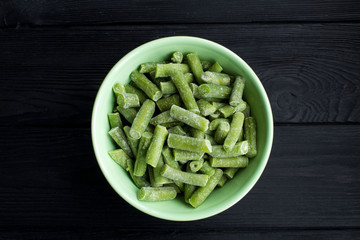 Frozen  asparagus  in the green  bowl  on the black wooden background.Top view.Copy space.Healthy food ingredient.