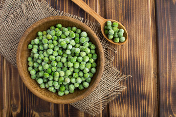 Frozen peas  in the brown bowl  on the  rustic wooden background.Top view.Copy space.Healthy food ingredient.