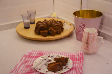 Homemade chocolate cake on plate. Slices of cake in pink kitchen. Interior design with pink flamingo