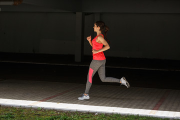 Obraz premium Female runner jogging trough parking lot.Fitness and jogging concept.