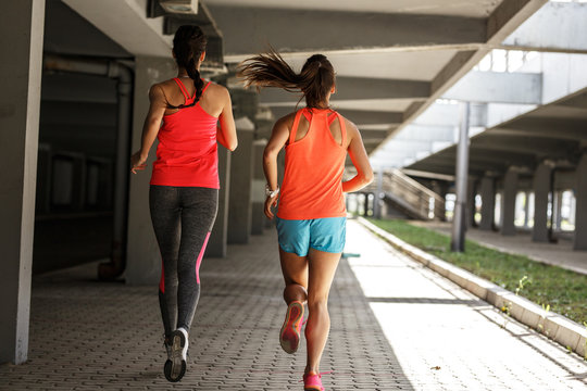 Two female runners jogging around the city.Urban workout concept.