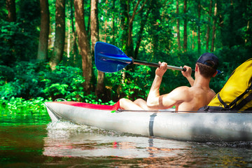 Man in kayak on river in wild forest. Kayaking with man in boat with oar.
