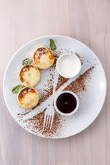 Cheese pancakes with currant jam and sour cream on a plate top view