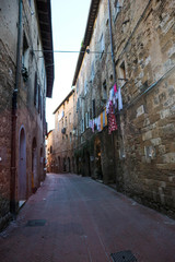Fototapeta premium Street in medieval town San Gimignano with drying clothes on the rope, Tuscany, Italy