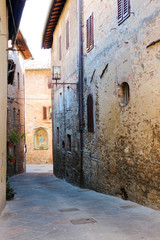 Narrow street with flowers in pots in medieval town San Gimignano, Tuscany, Italy