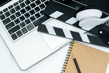 Movie maker with movie editing device,laptop, earphone, movie clapper board, note pad on white...