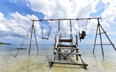 Indonesian girl on a swing at Pantai Tanjung Kelayang Beach, Belitung Island, Indonesia