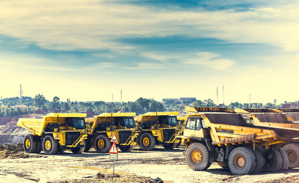 Yellow dumper trucks in mine of Riotinto put in row, with traffic signal of exit of trucks in foreground
