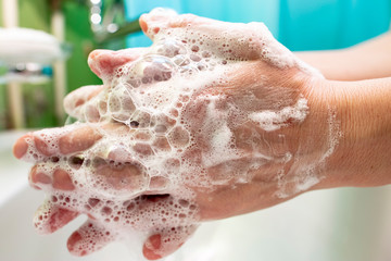 Washing hands with soap suds, on a blurred background. Close-up.