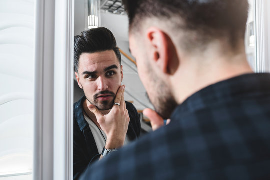 Handsome man at fashion stylist salon in front of mirror looking himself