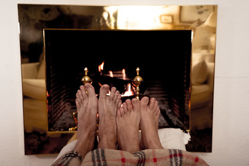 Obraz premium Close up of couple feet warming up by the fireplace in winter vacation and happy moments together