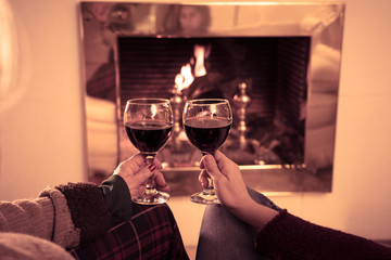 Close up of happy couple drinking wine by fire place celebrating love and winter holidays vacation