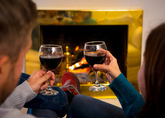 Close up of happy couple drinking wine by fire place celebrating love and winter holidays vacation