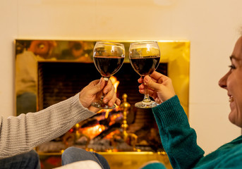 Close up of happy couple drinking wine by fire place celebrating love and winter holidays vacation