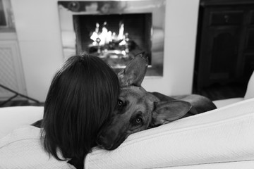 Cute portrait of young woman and dog german shepherd hugging at cozy home in winter