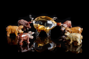 Pig figurines made of onyx, jasper, glass, gold on a black background
