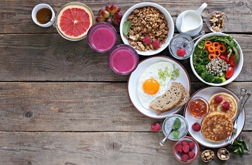 Brunch or breakfast table. Festive brunch set, meal variety with quinoa salad bowl, fried egg, granola, pankes, chia seeds pudding and smoothy  . Overhead view