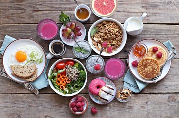 Brunch or breakfast table. Festive brunch set, meal variety with quinoa salad bowl, fried egg, granola, pankes, chia seeds pudding and smoothy  . Overhead view