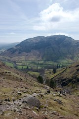 Fototapeta na wymiar Rocky grass mountain moorland in foreground; pastoral fields below in mountain valley