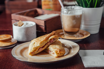 Baking puff pastry with pieces of pork inside and a transparent cup with cocoa nearby