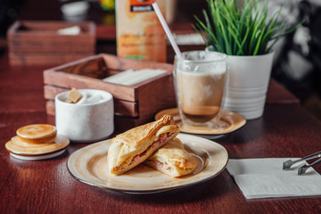 Baking puff pastry with pieces of pork inside and a transparent cup with cocoa nearby