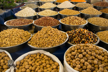 Assorted nuts (almond, hazelnut, cashew, pistachio, chickpea, walnut, peanut, sunflower seeds) in bowls at farmers market. Vegan food background