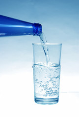 Mineral water pours from the bottle into the glass