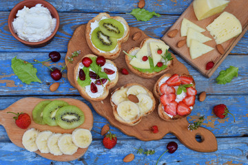 Set of healthy whole wheat bread sandwiches with fuits, vegetables, cheese and leafy green herbs on picnic wooden table. Ciabatta sandwich bar. Top view. Lunch time snacks concept. Vegetarian food