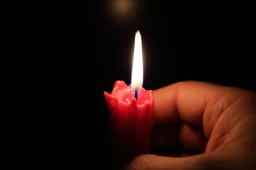 Red candle burns on a black background.