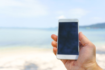 mobile phone in hand on background of blue sea