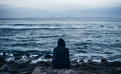 Lonely sad person sitting in front of the sea