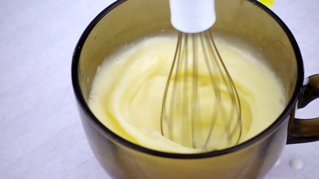 Electric mixer whip milk and eggs in glass bowl close up. Cooking omlet in slow motion.
